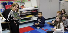 Parent volunteer reading to kindergarten students.